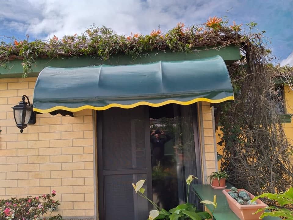 Cenefa verde con ribete amarillo sobre la entrada de una casa